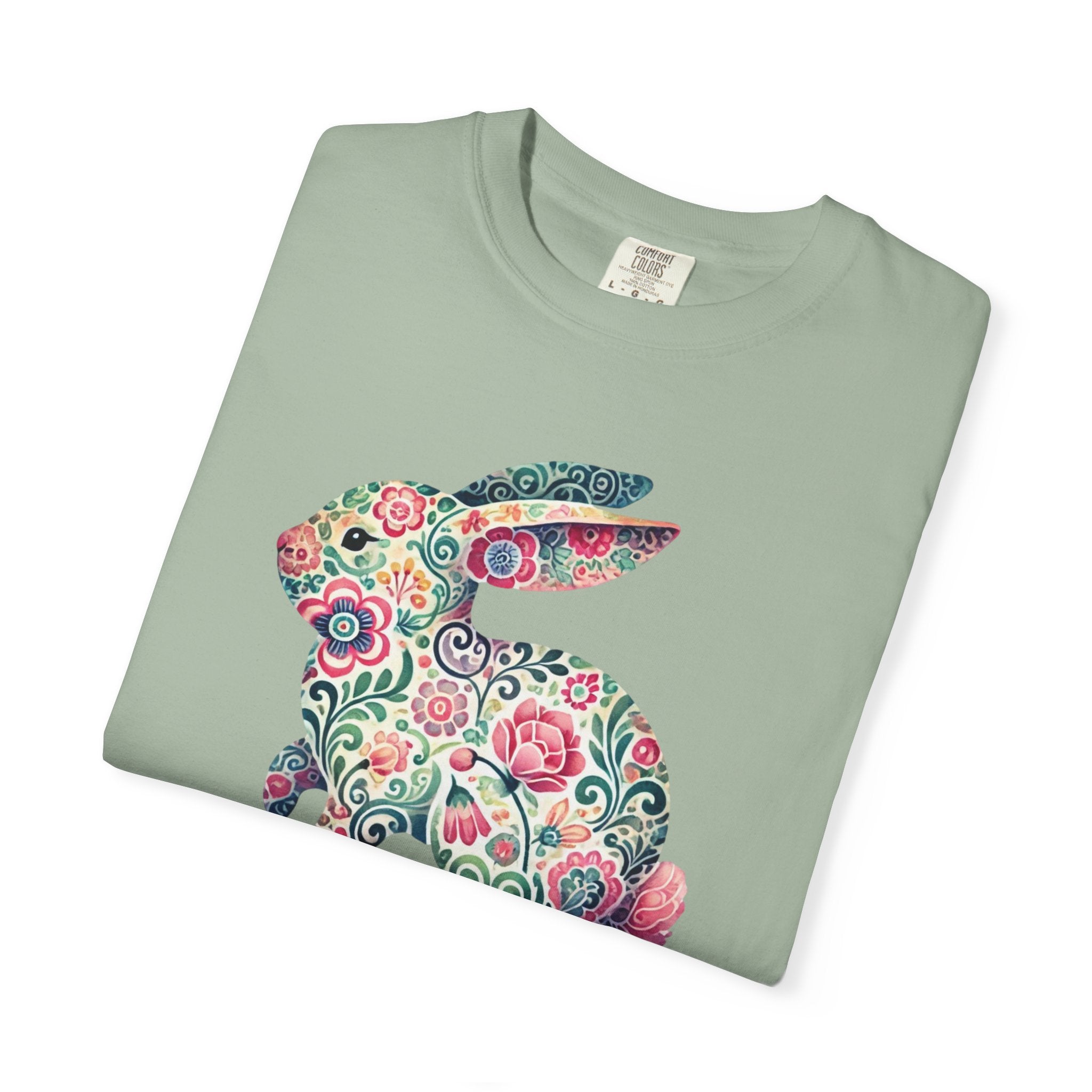 Folded green t-shirt with a colorful floral bunny design on a white background