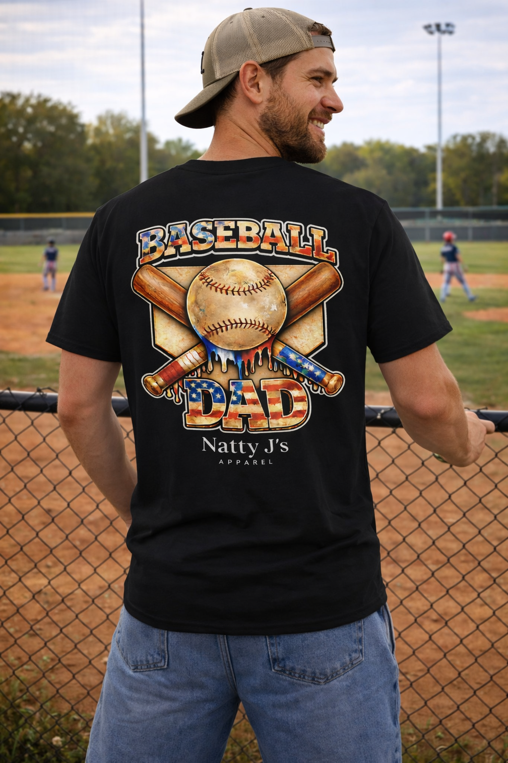 Man wearing a black t-shirt with 'Baseball Dad' design on a baseball field.