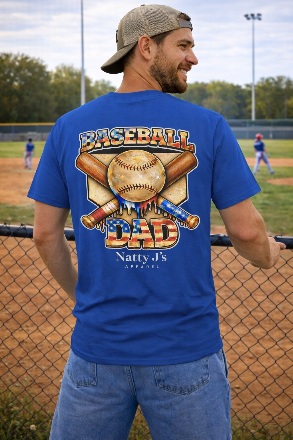 Man wearing a blue 'Baseball Dad' t-shirt on a baseball field