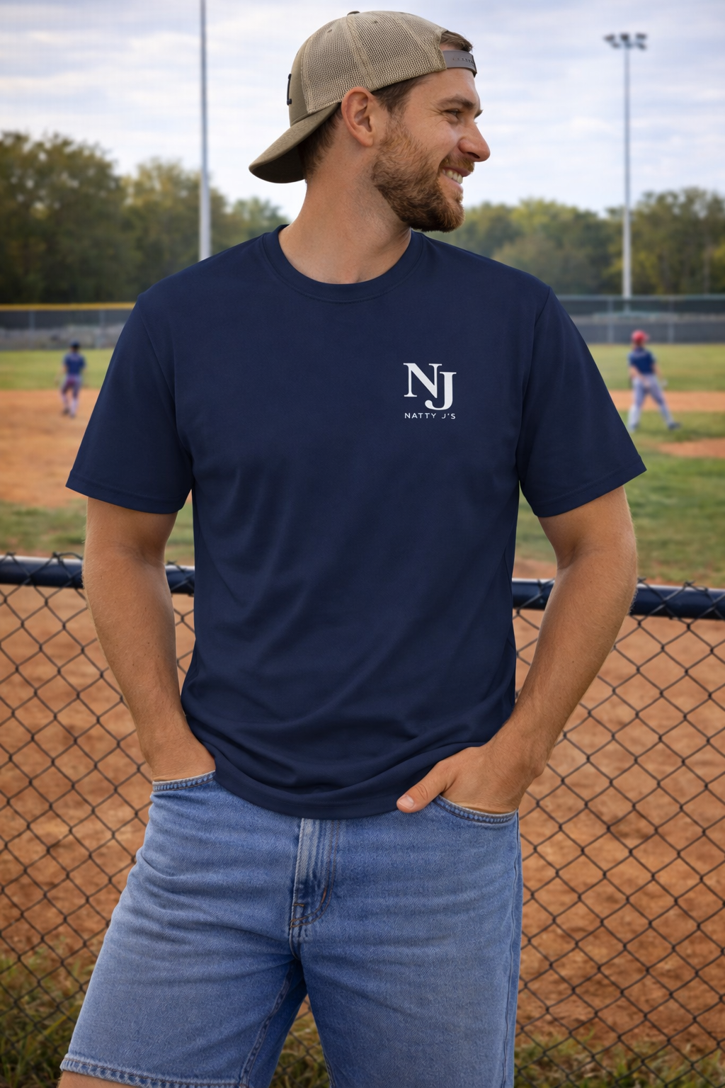 Man wearing a navy blue t-shirt with a logo on a baseball field