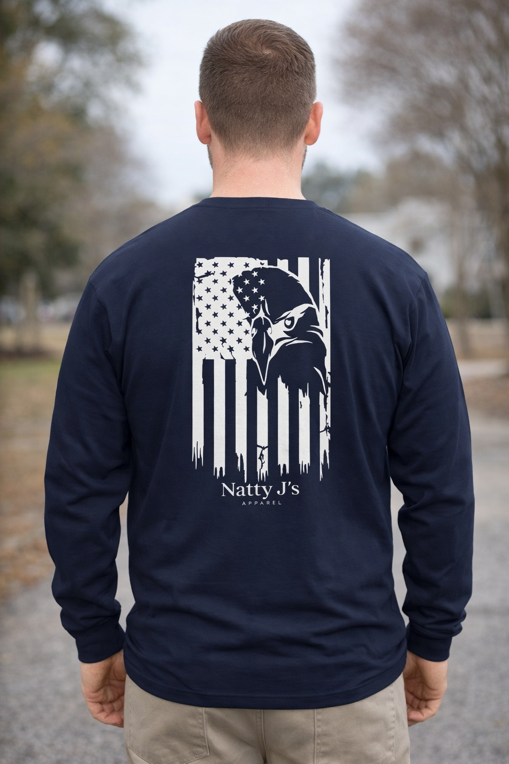 Person wearing a navy long-sleeve shirt with a white graphic design on the back, standing outdoors.