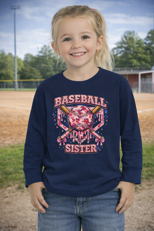 Young girl wearing a navy sweatshirt with 'Baseball Sister' design on a baseball field.