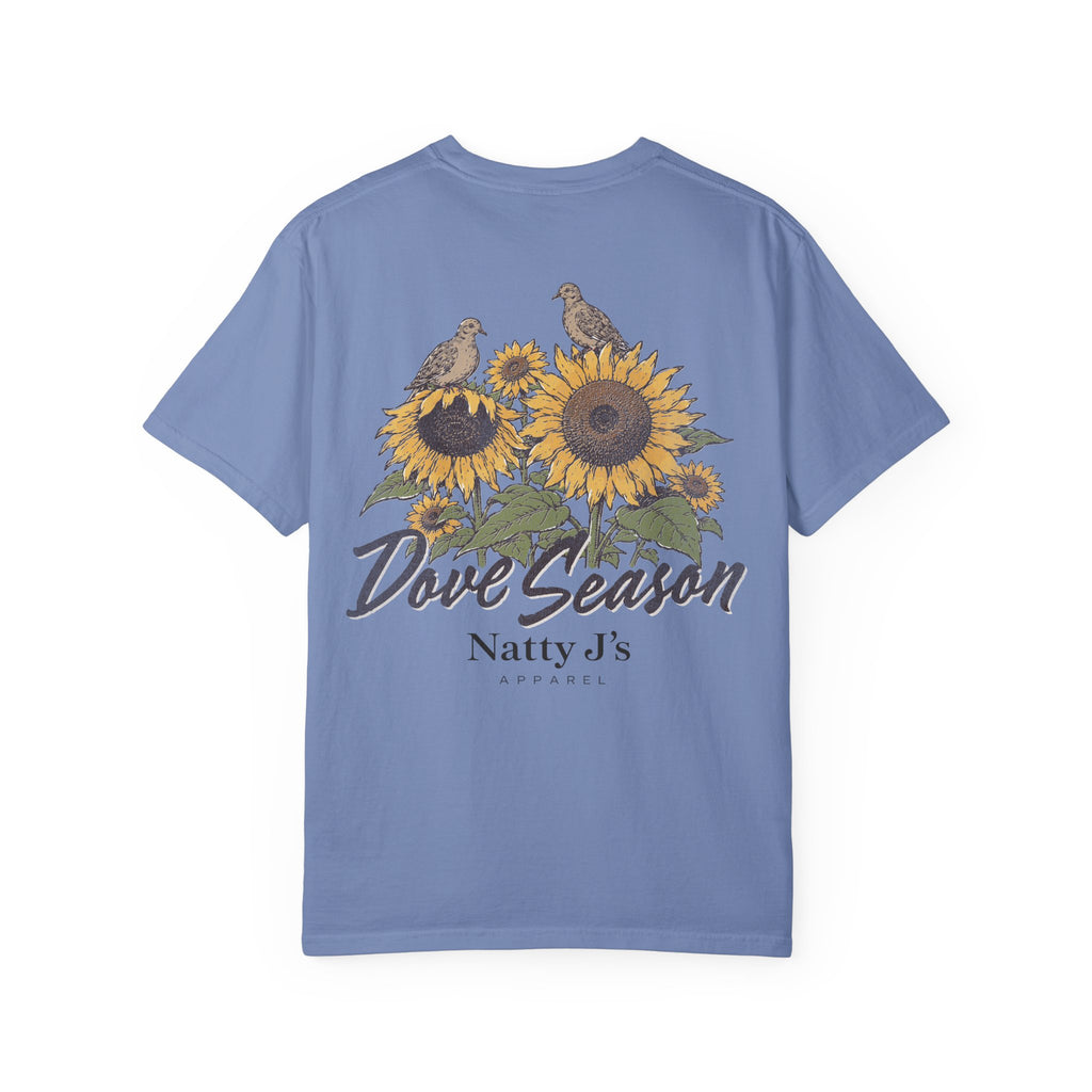 A light blue short-sleeve t-shirt with a graphic on the back featuring two doves perched on sunflowers, with the text 'Dove Season' and 'Natty J's APPAREL' printed below.