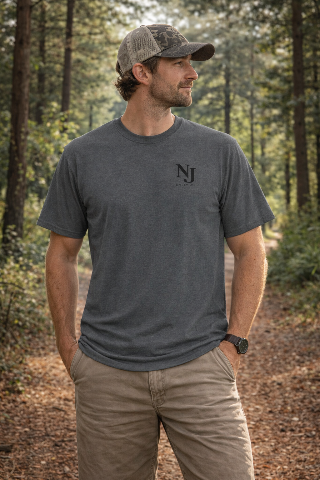 Man wearing a gray t-shirt with 'NJ' logo in a forest setting