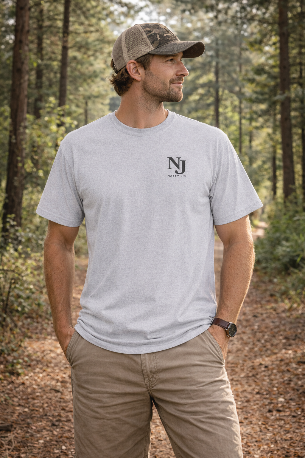 Man wearing a gray t-shirt with a logo in a forest setting
