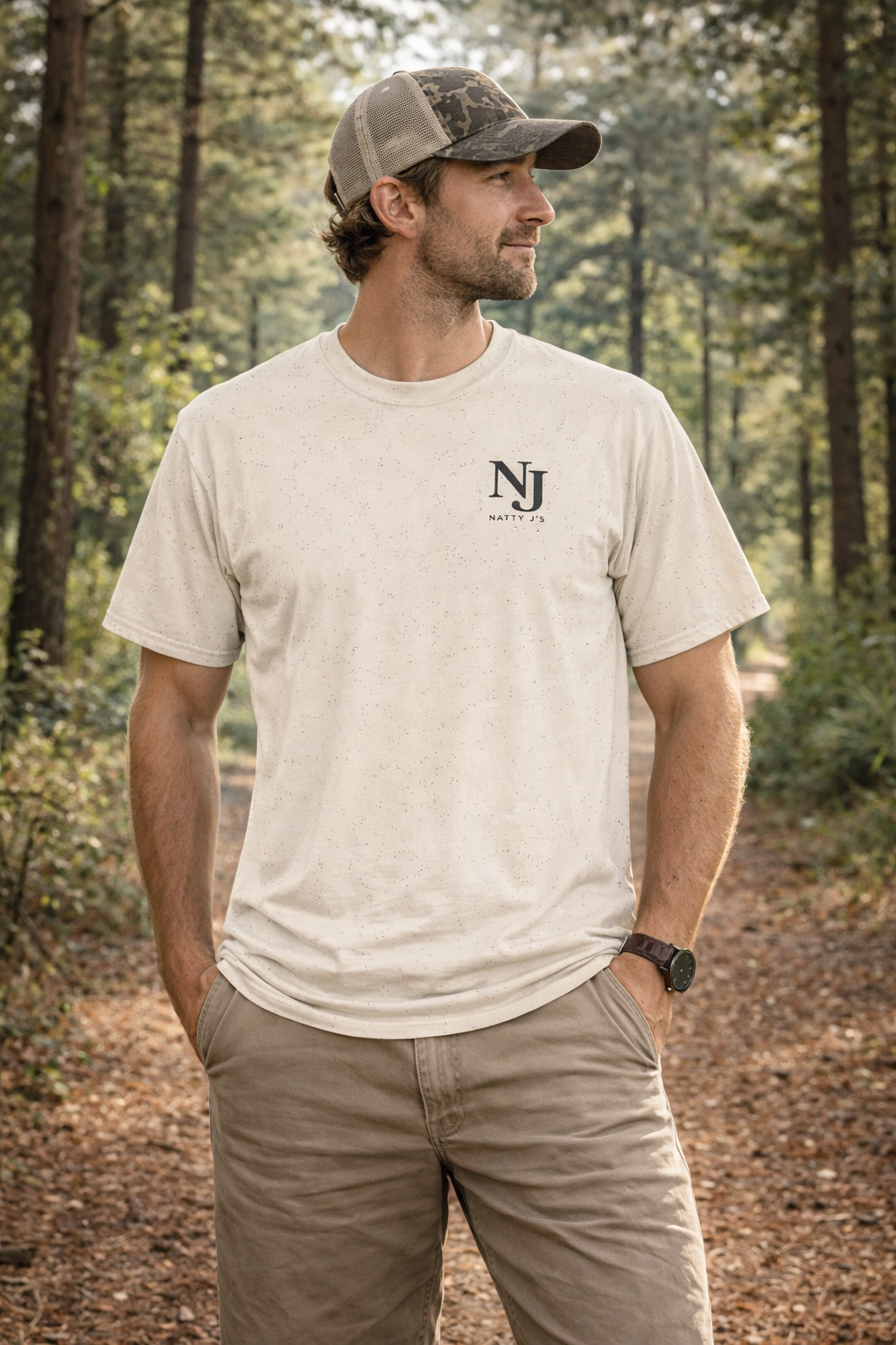 Man wearing a beige t-shirt with a logo in a forest setting