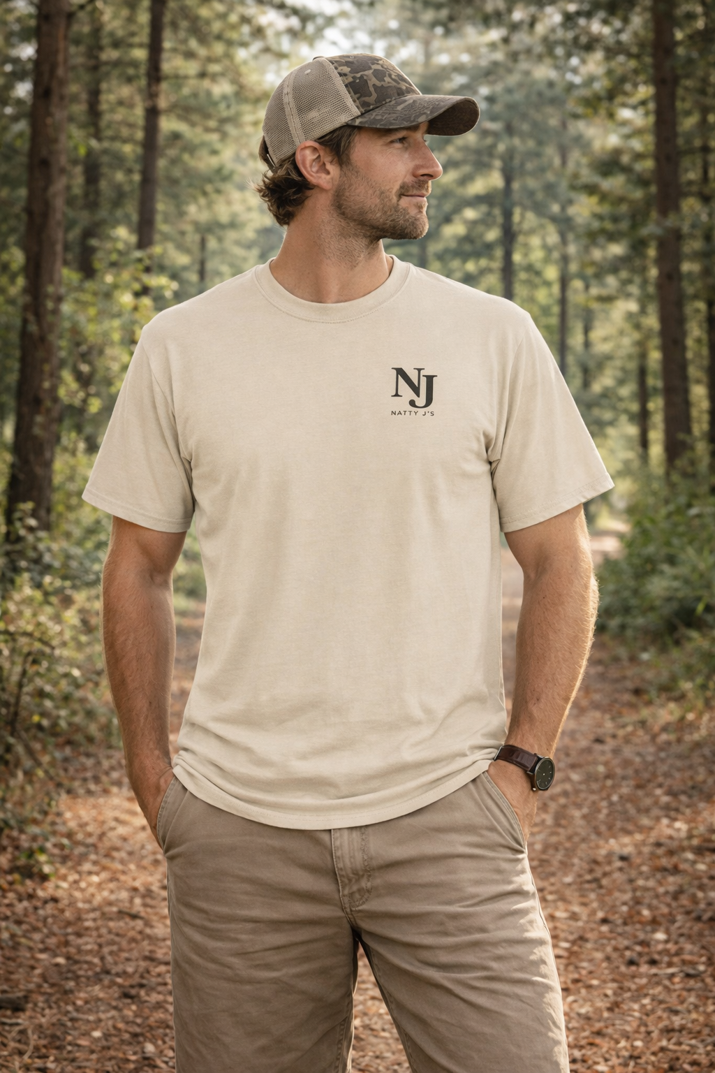 Man wearing a beige t-shirt with a logo in a forest setting