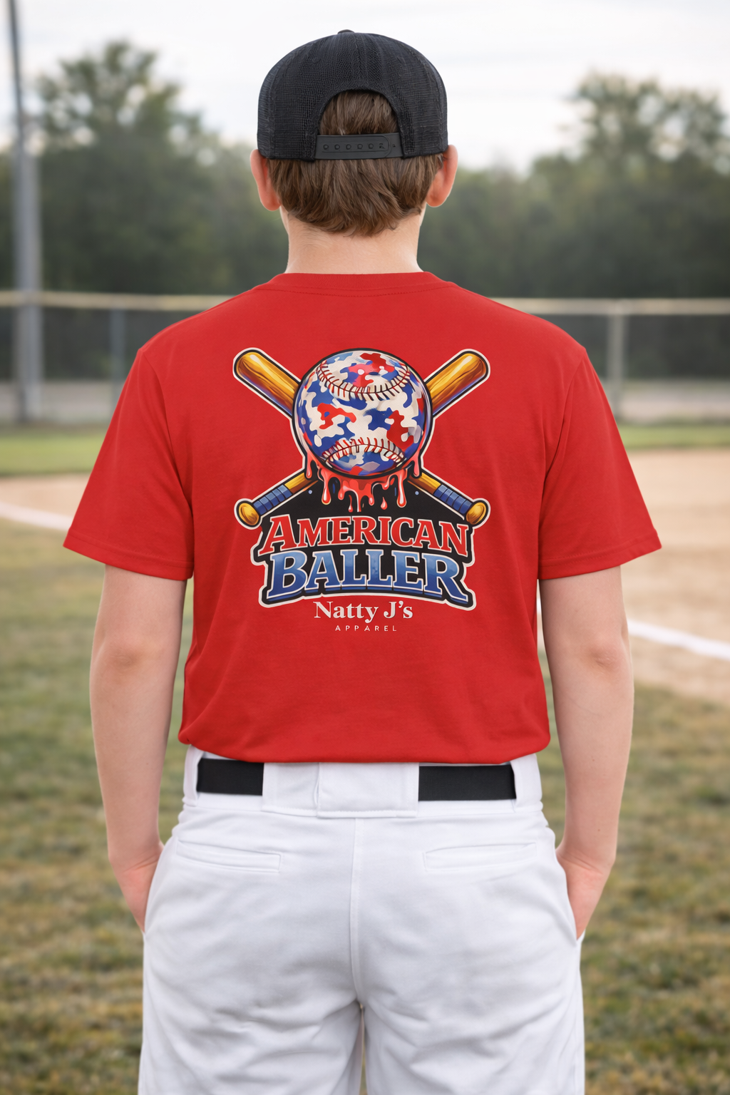 Person wearing a red 'American Baller' t-shirt with a baseball design on a baseball field.
