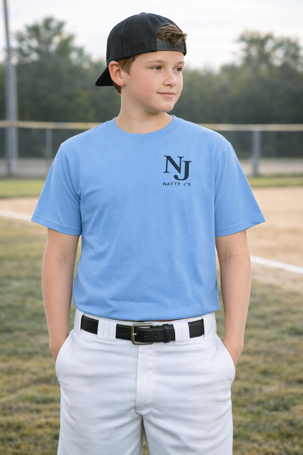 Young boy wearing a blue t-shirt with 'Natty Joe' logo on a baseball field.