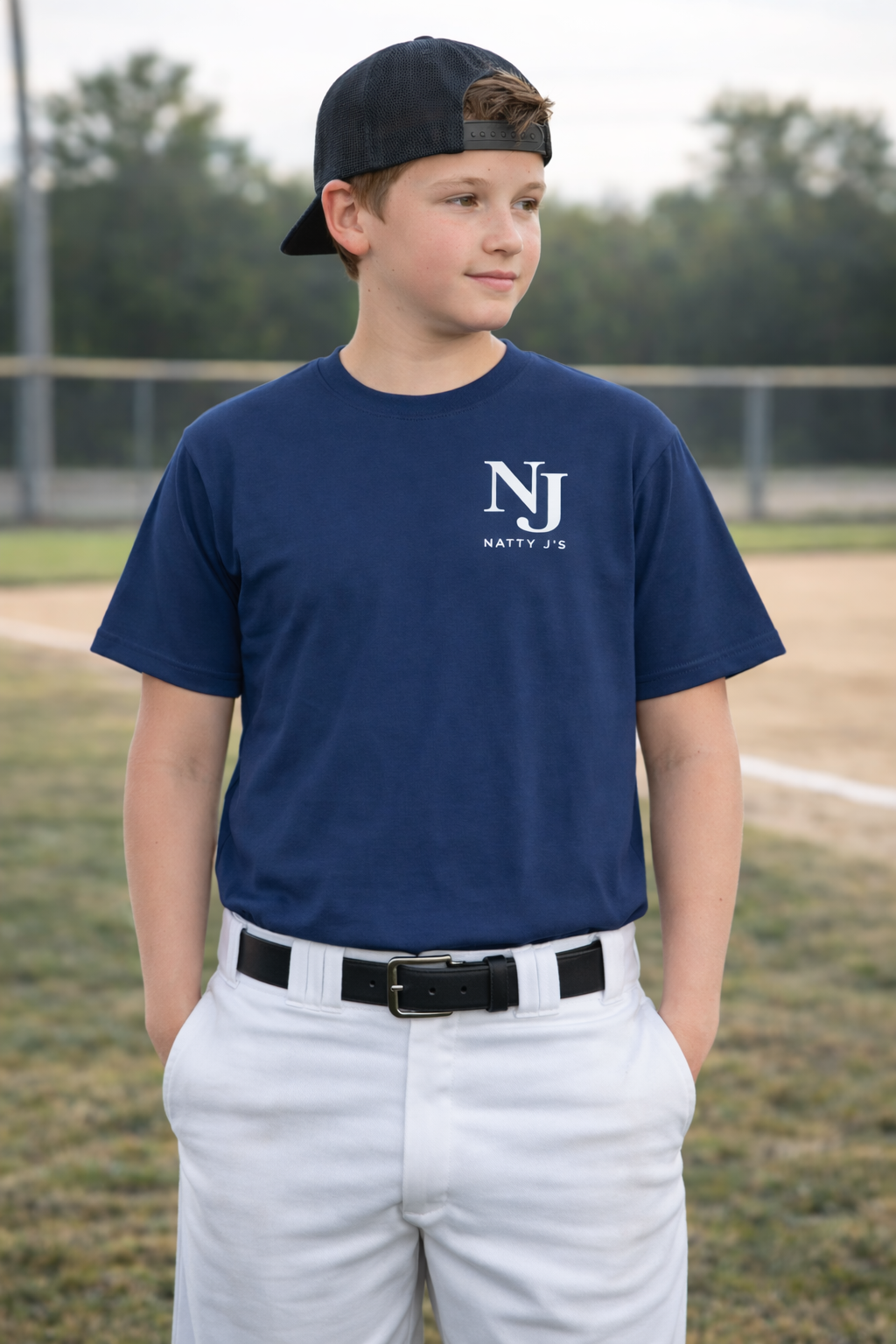Young boy wearing a navy blue sports jersey with a logo on a baseball field