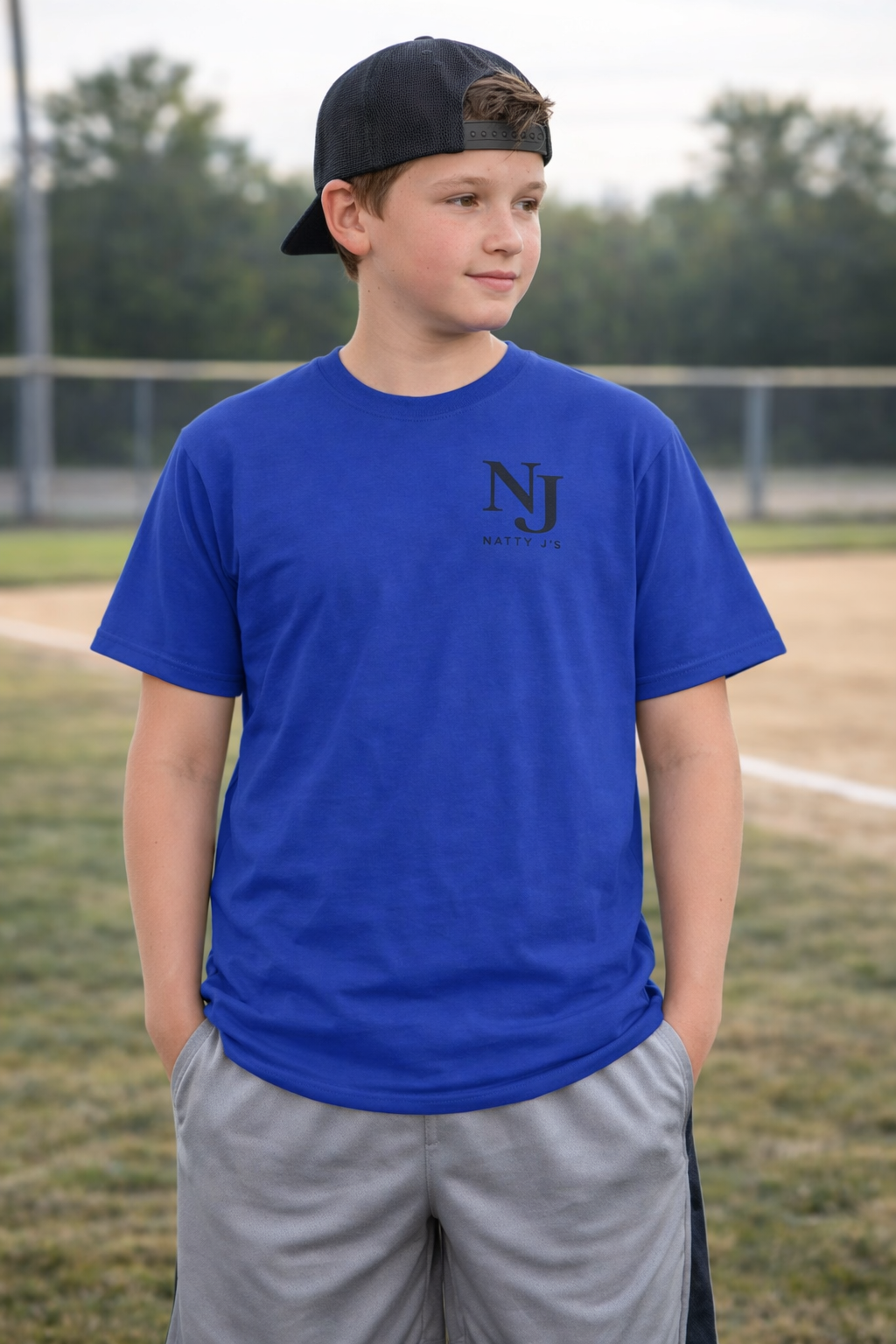 Young boy wearing a blue t-shirt with a logo on a sports field
