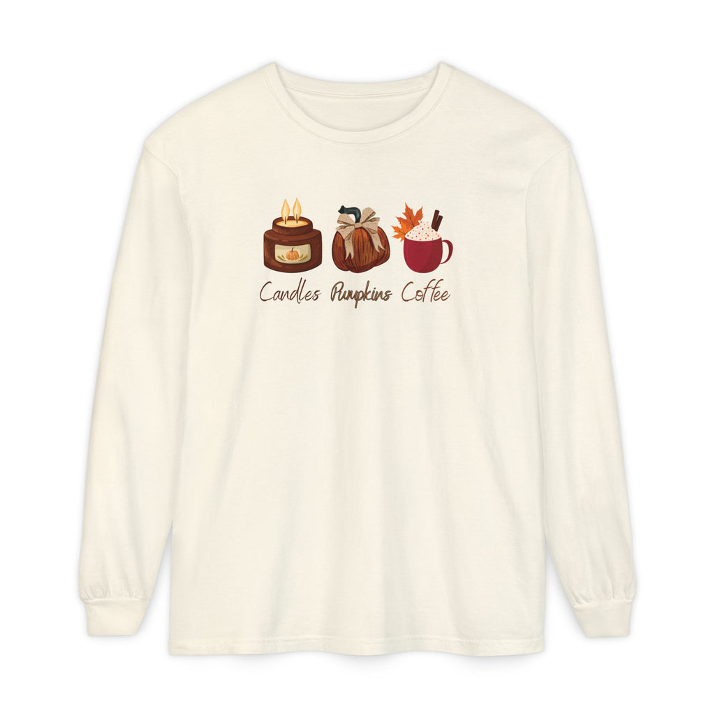 An off-white long-sleeve t-shirt with a graphic of three cozy autumn-themed items: a candle, a pumpkin lantern, and a mug of pumpkin coffee, with the text 'Candles Pumpkin Coffee' printed below.