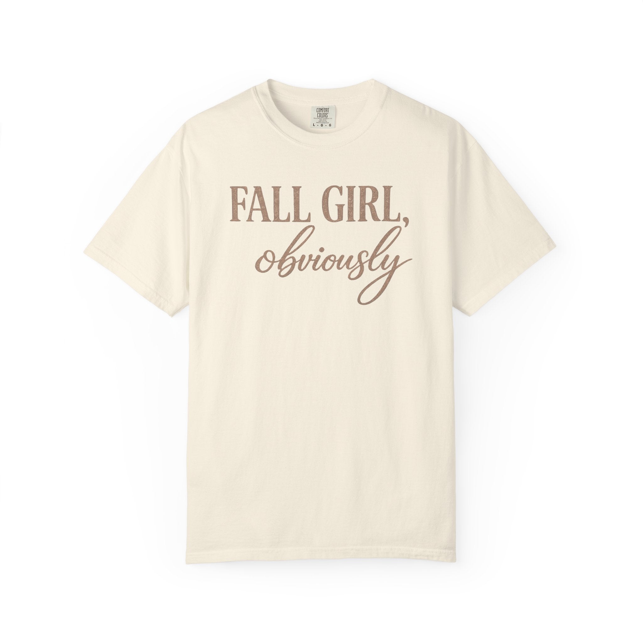 An off-white short-sleeve crewneck t-shirt with the text 'FALL GIRL, obviously' printed on the chest in a dusty rose-brown color, displayed against a solid white background.