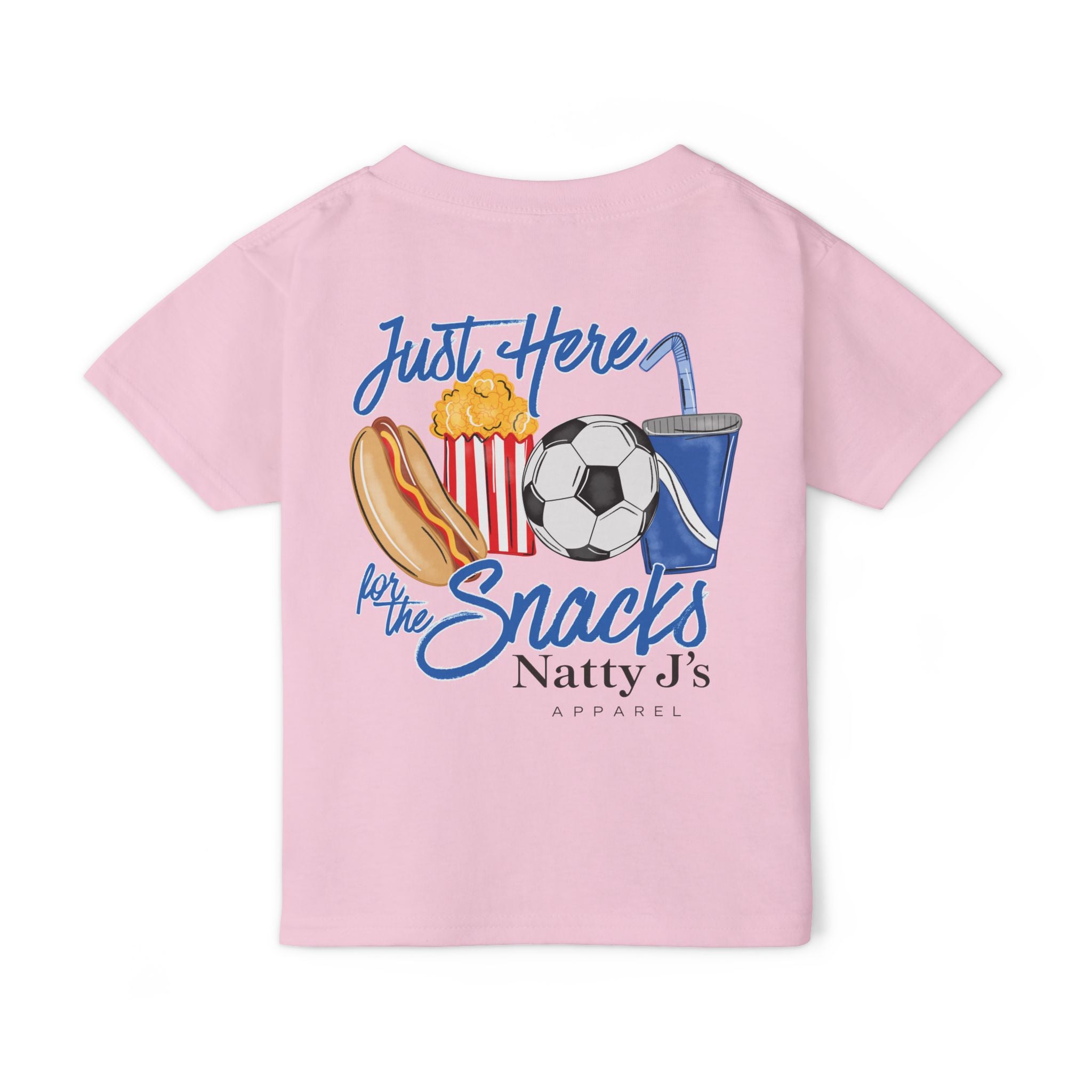 A light pink short-sleeve t-shirt with a colorful graphic on the back featuring a hot dog, popcorn, soccer ball, and a blue drink cup, with the text 'Just Here for the Snacks' and 'Natty J's APPAREL'.