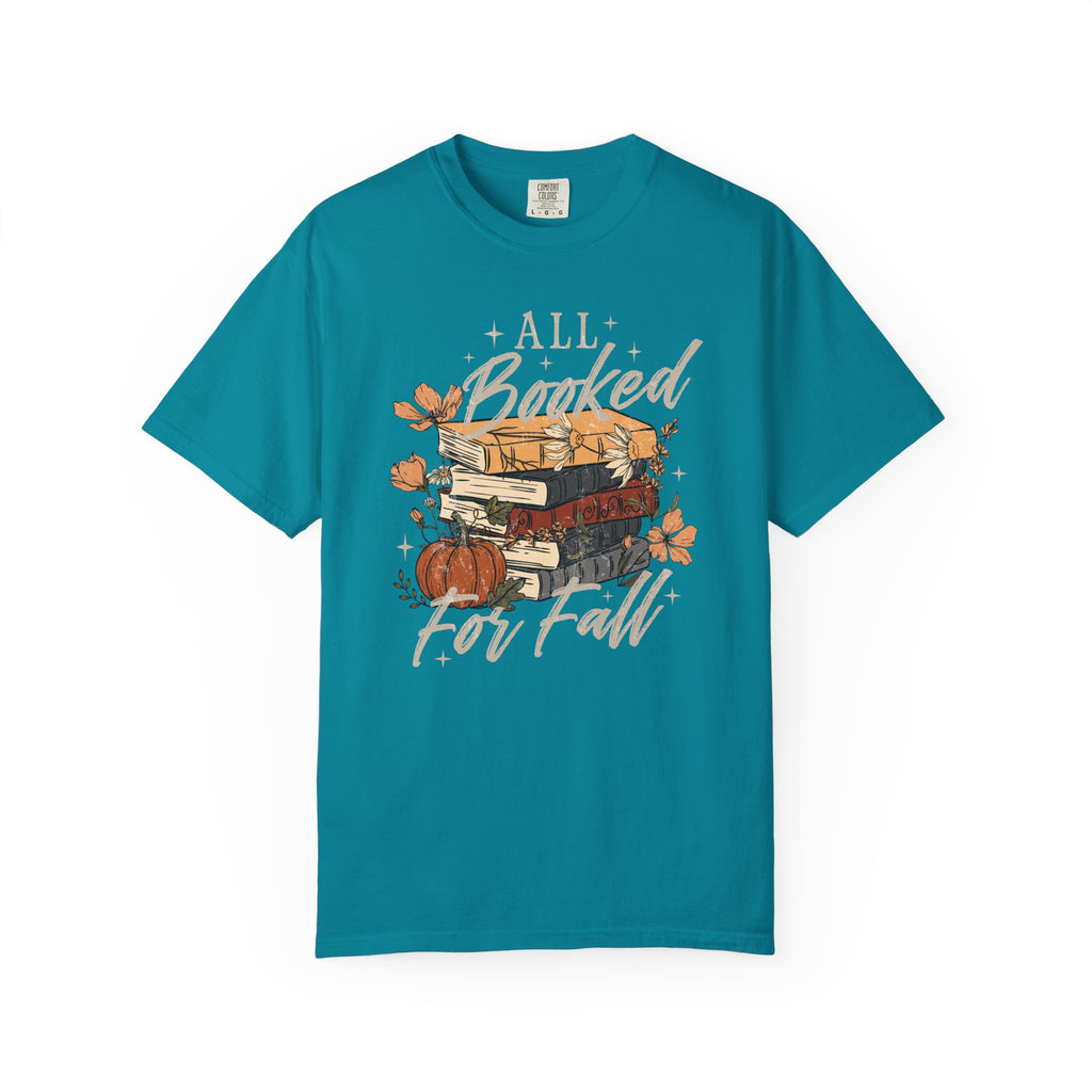 A teal short-sleeve t-shirt with a graphic on the front featuring a stack of books, autumn leaves, a pumpkin, and the text 'ALL Bunked For Fall' in white script, displayed on a clean white background.
